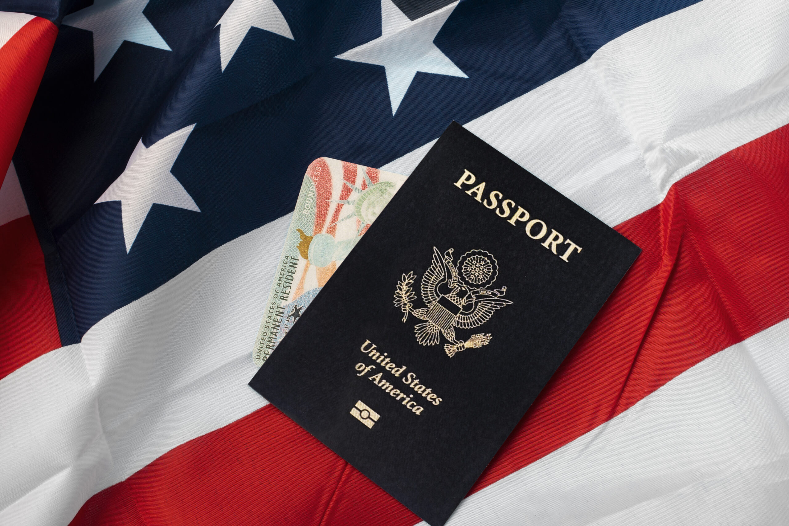 U.S. passport and Permanent Resident Card on an American flag