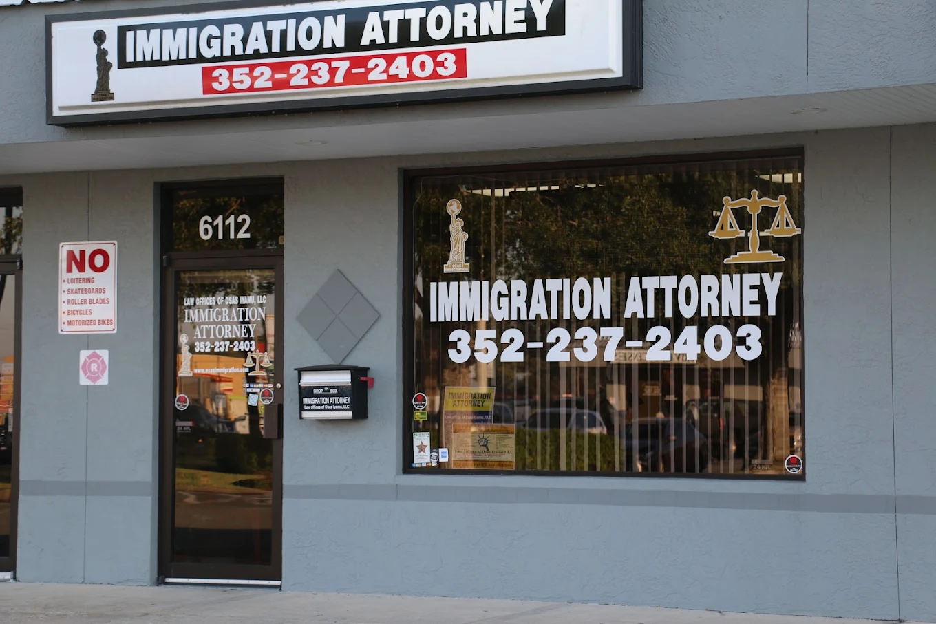 Entrance to Law Offices of Osas Iyamu in Jasmine Square, showing street number 6112 and the Immigration Attorney sign.